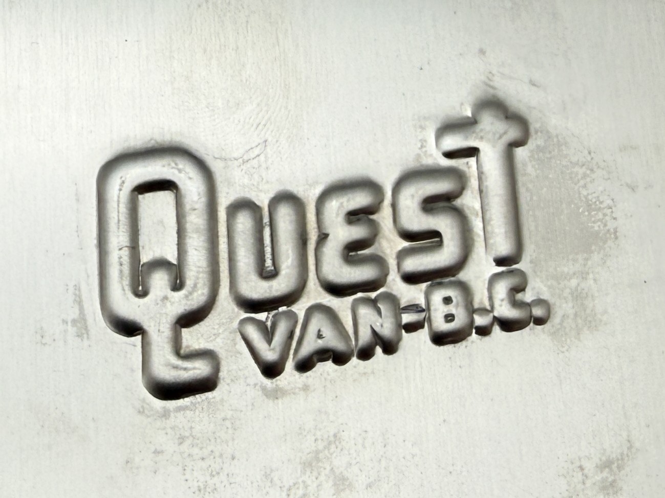 Front view of custom embossed Quest stainless steel logo with raised lettering