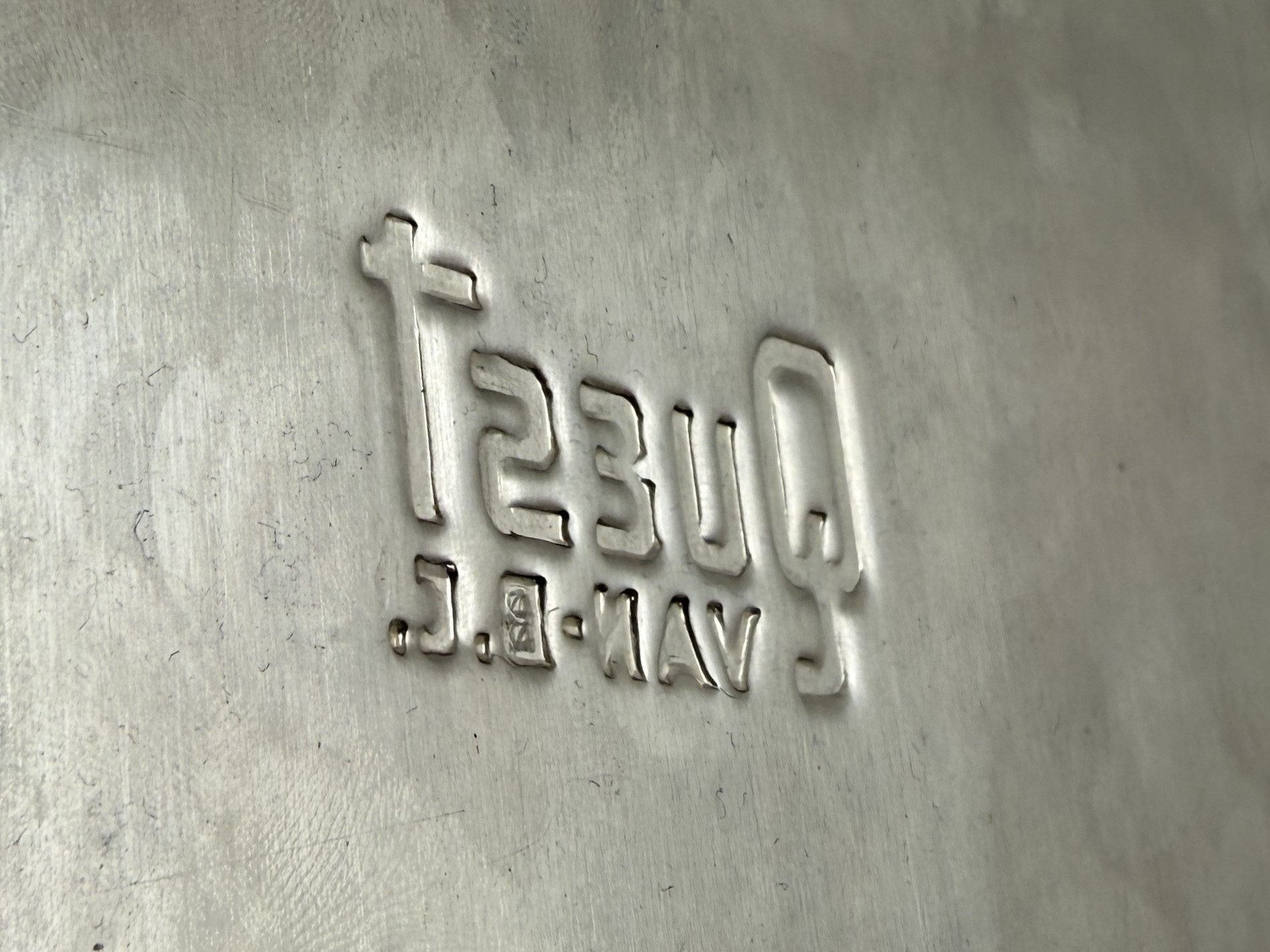 Back side view of embossed Quest stainless steel logo showing indented mirror image characters